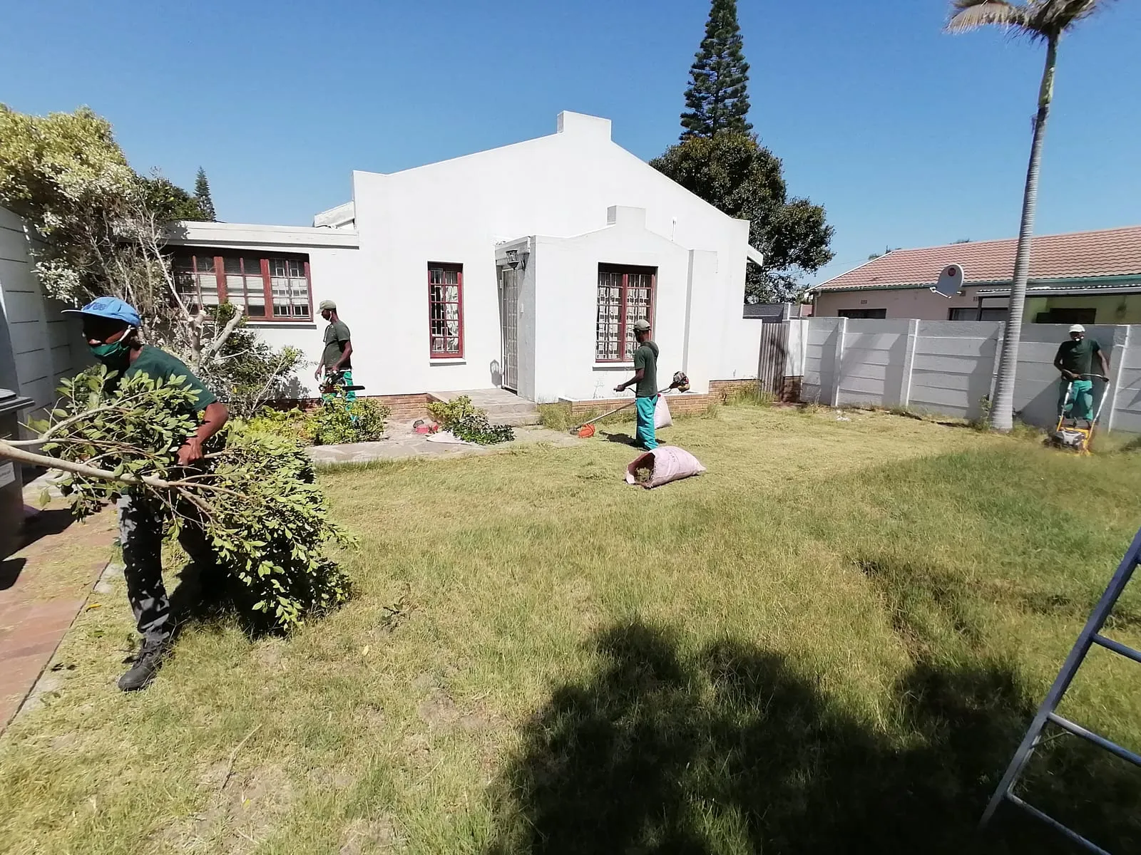 Crew members carrying away hedge cuttings